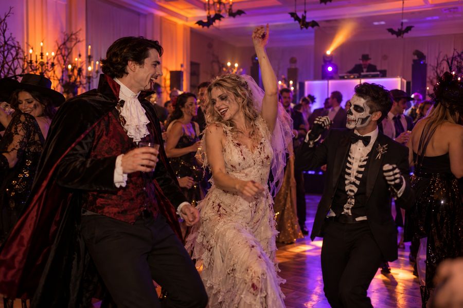 Adults in elaborate costumes dancing at a Halloween party.
